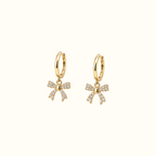DUGO gold huggie earrings featuring dangling crystal-encrusted ribbon bows for an elegant feminine look.