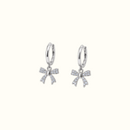DUGO silver huggie earrings featuring dangling crystal-encrusted ribbon bows for an elegant feminine look.