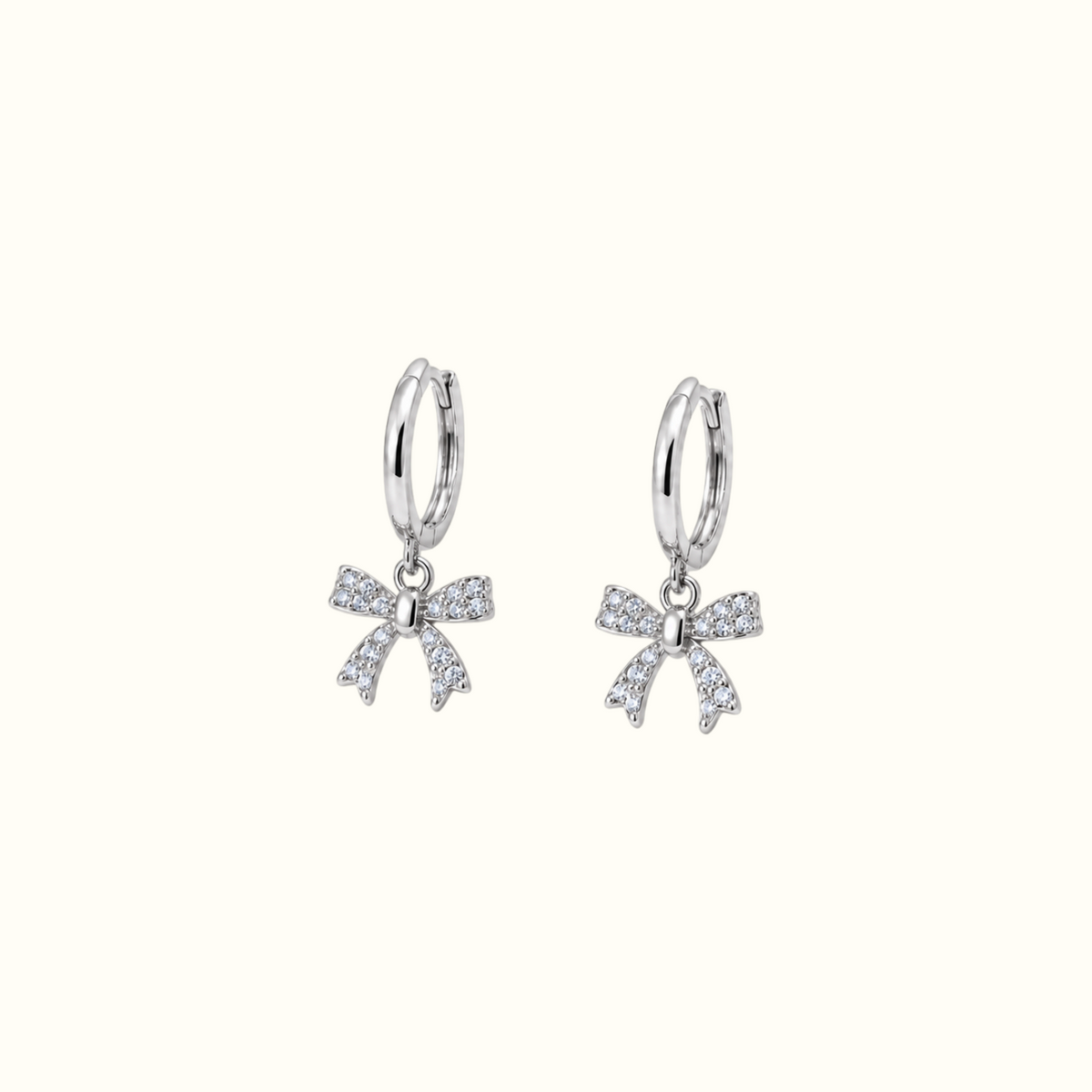 DUGO silver huggie earrings featuring dangling crystal-encrusted ribbon bows for an elegant feminine look.