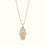 DUGO gold Hamsa hand evil eye pendant necklace featuring sparkling cubic zirconia stones on a delicate chain