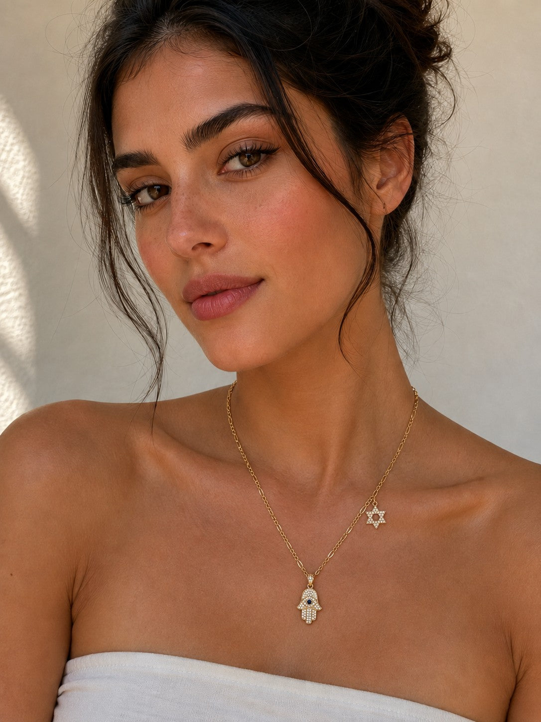 Close-up of the DUGO gold Hamsa with Star David Charm Necklace worn on the neck