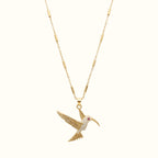 DUGO gold hummingbird pendant necklace featuring a delicate tube chain and sparkling crystal accents.