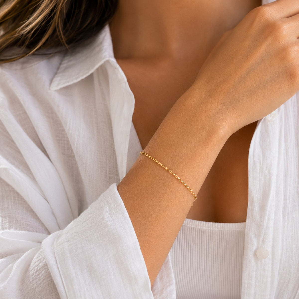 DUGO dainty 18K gold filled Venetian chain bracelet worn on a woman's wrist with a white shirt