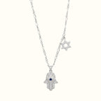 DUGO silver-tone Hamsa hand necklace with a blue evil eye, crystal accents, and a Star of David charm on a chain.