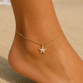 DUGO Starfish Anklet featuring a pavé crystal starfish charm on a delicate 18K gold beaded chain worn on the beach.