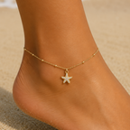 DUGO Starfish Anklet featuring a pavé crystal starfish charm on a delicate 18K gold beaded chain worn on the beach.