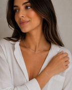 DUGO dainty silver curb chain bracelet worn by a woman in a white shirt, minimalist waterproof stainless steel design