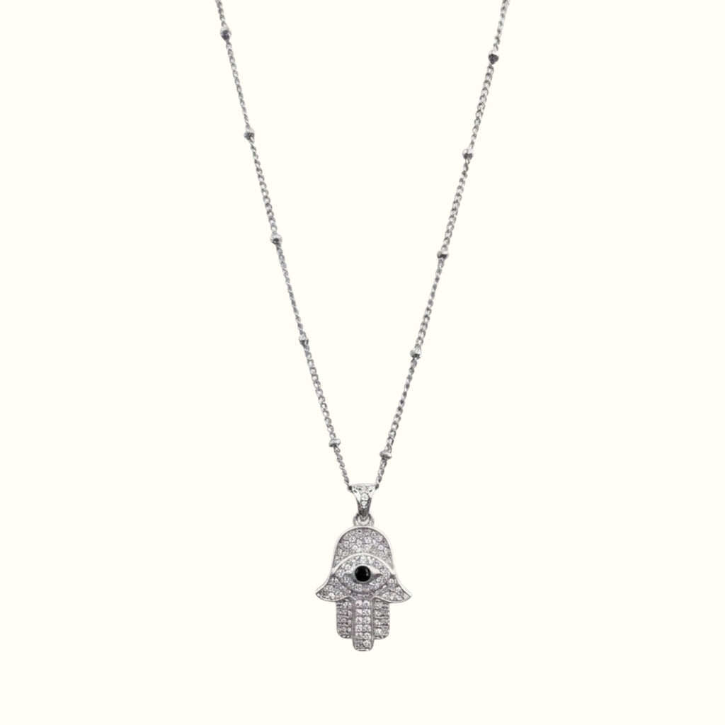 DUGO silver hamsa hand necklace with cubic zirconia stones and a black evil eye center on a delicate beaded chain.
