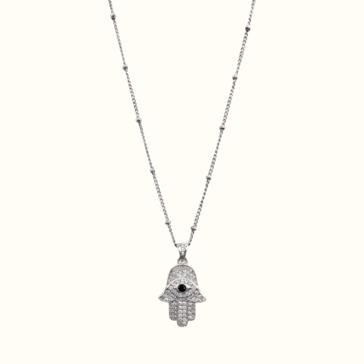 DUGO silver hamsa hand necklace with cubic zirconia stones and a black evil eye center on a delicate beaded chain.