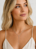 DUGO silver lariat necklace with delicate heart accents worn by a blonde woman in a white camisole