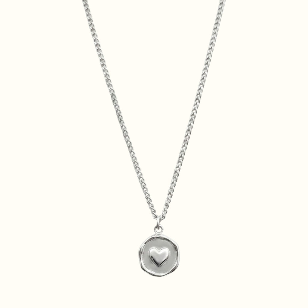 DUGO silver heart plate necklace featuring a small raised heart charm on a delicate circular pendant and chain