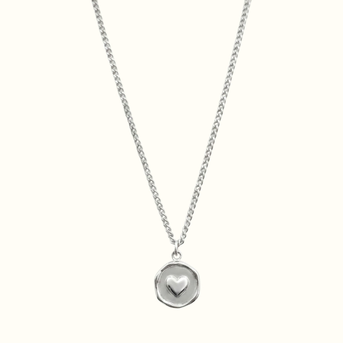 DUGO silver heart plate necklace featuring a small raised heart charm on a delicate circular pendant and chain