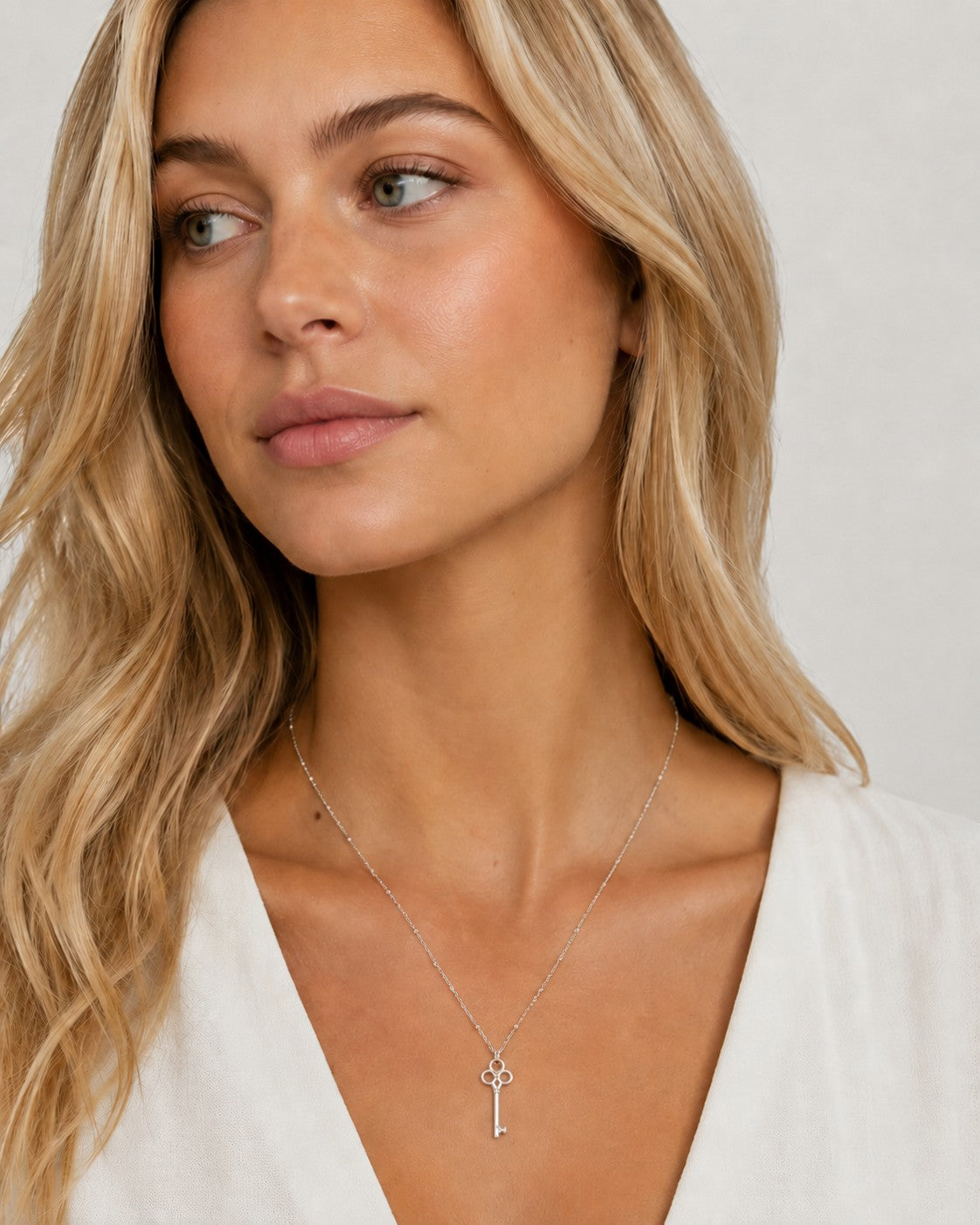 DUGO silver vintage key pendant necklace on a dainty ball chain worn by a blonde woman in a white top