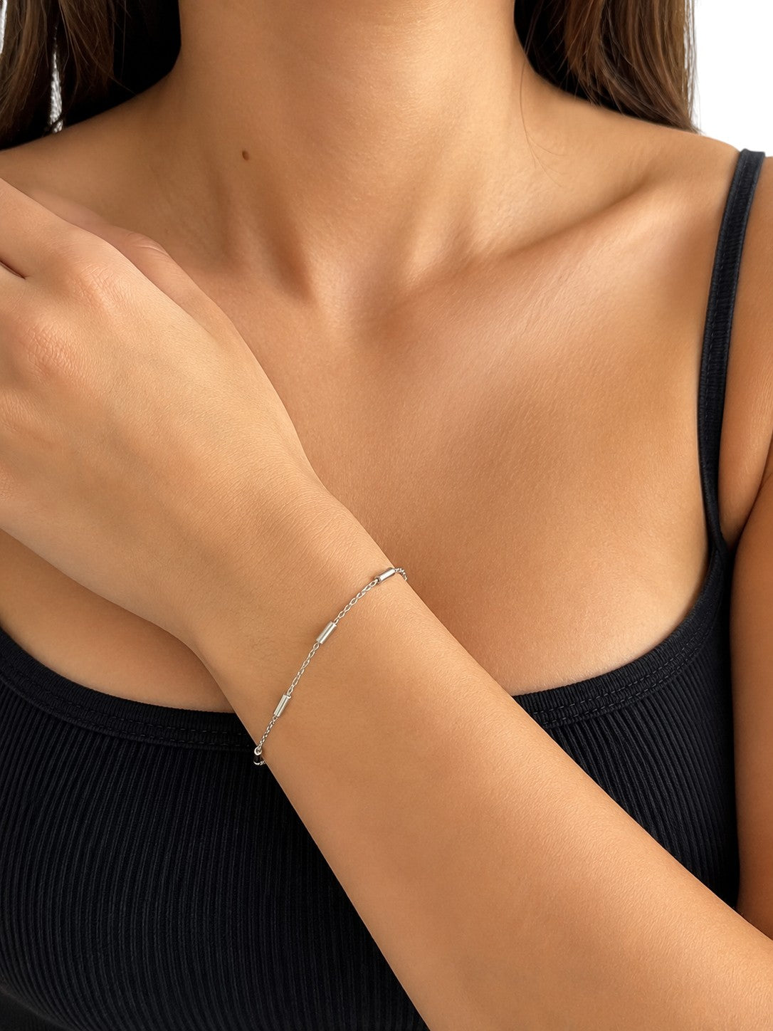 DUGO minimalist tube station chain bracelet in silver-tone stainless steel worn on a woman's wrist